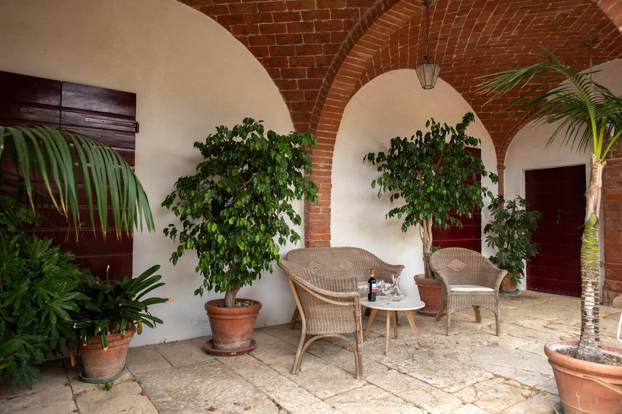 Covered loggia terrace with wicker chairs at Podere Casanova