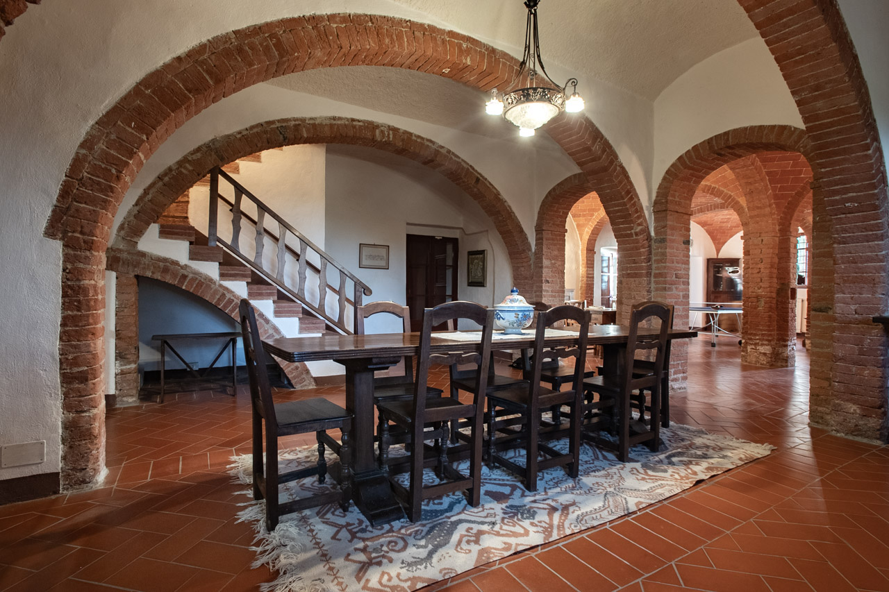 Grand hall with brick arches and long dining table at Podere Casanova